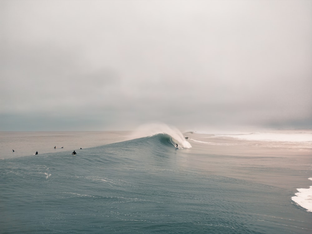 a group of people riding a wave on top of a surfboard