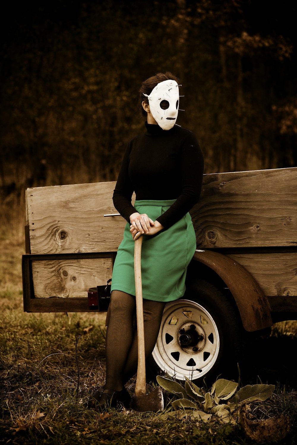Una mujer sentada en un banco con una máscara y sosteniendo un bate de béisbol