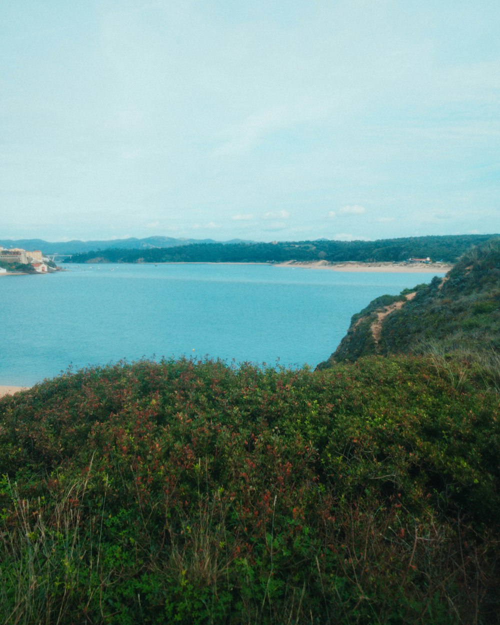 a large body of water sitting next to a lush green hillside