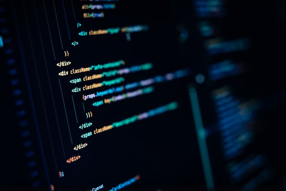 Close-up of computer code displayed on a dark monitor, with highlighted syntax in various colors for readability and structure. Lines of code appear in HTML format, demonstrating coding techniques.