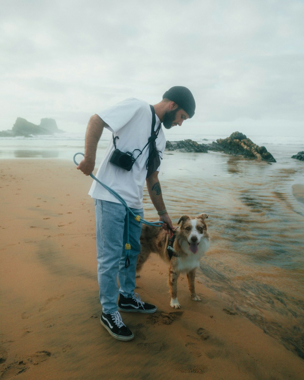 a man on a beach with a dog on a leash