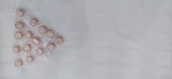 A group of peppermint candies arranged in a triangular pattern on a textured white surface. The candies are individually wrapped and have a red and white striped pattern.
