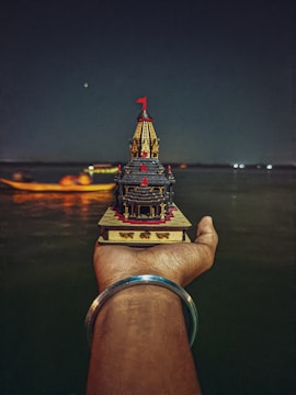 Close-up of a hand-painted temple replica with tiny LED lights highlighting the windows.