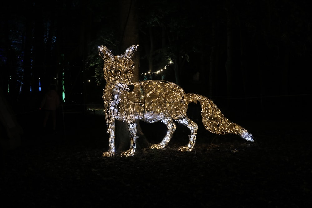a lighted deer in the dark with trees in the background