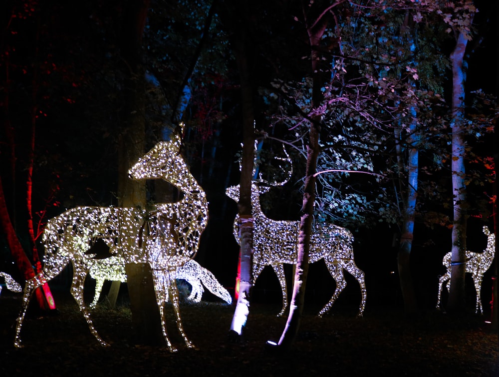 a group of deer statues in a forest at night