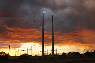 Photo of a technician inspecting electrical infrastructure with a sunset in the background.