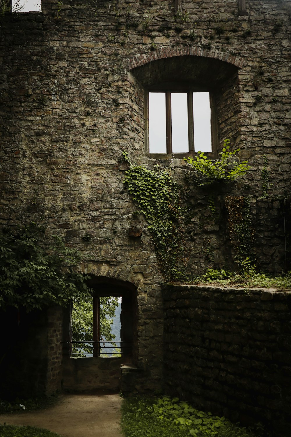 an old brick building with a window and ivy growing up the side of it