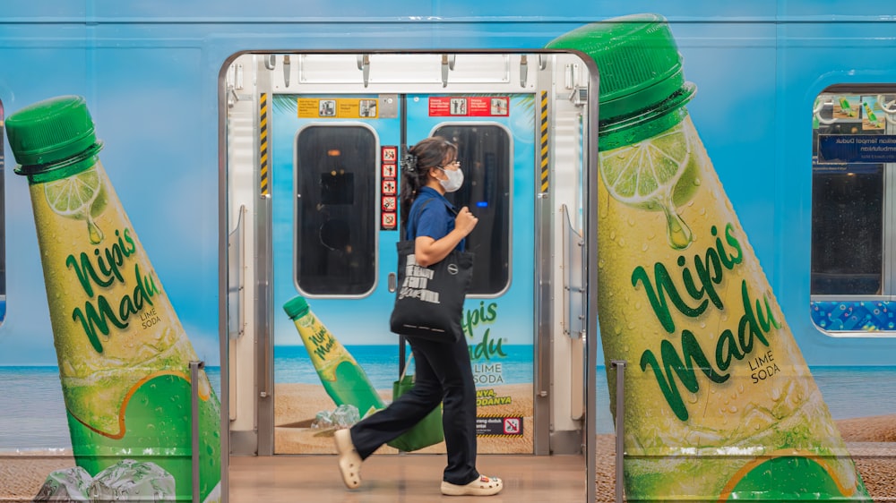 a woman walking past a train with a large advertisement on the side of it