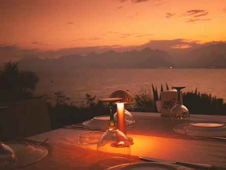 A bright, elegant dining setup overlooking a scenic South African landscape at sunset.