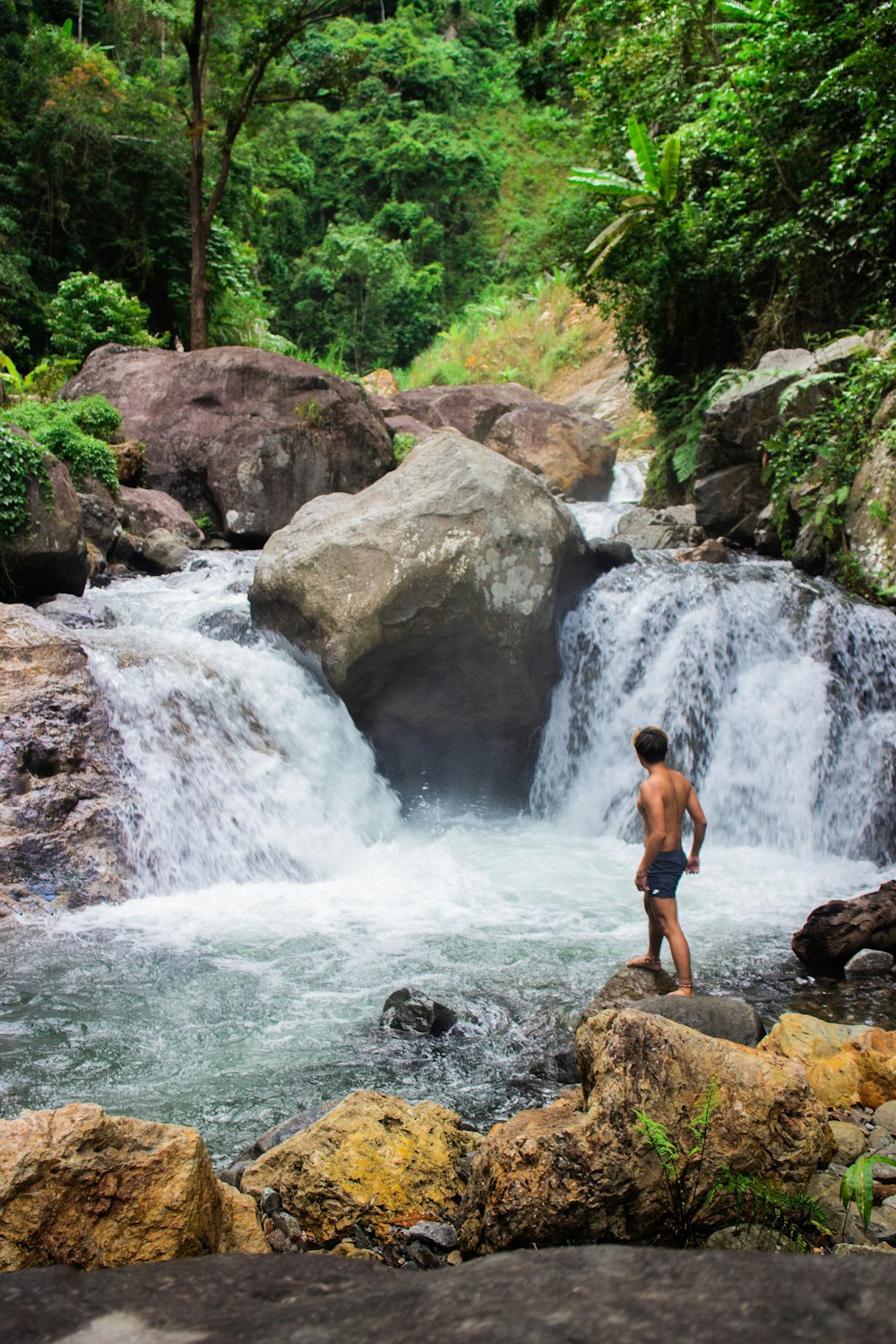 a man standing on a rock next to a waterfall