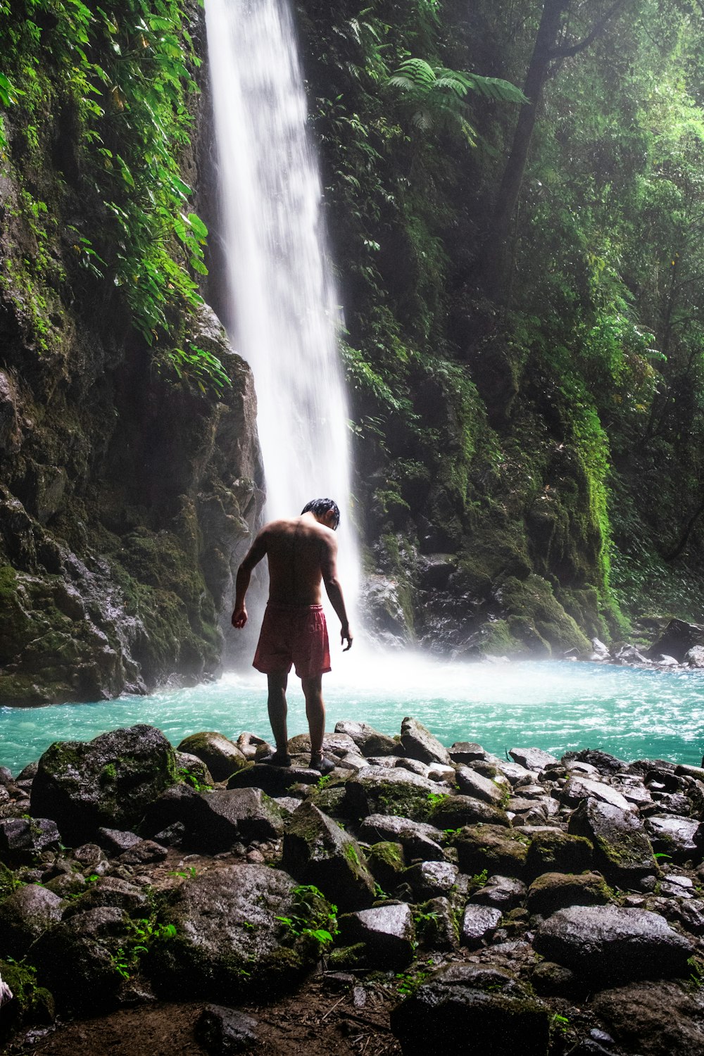 Un hombre parado frente a una cascada