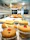 Photo of a small business owner arranging a display of vibrant jar cakes with a joyful expression.