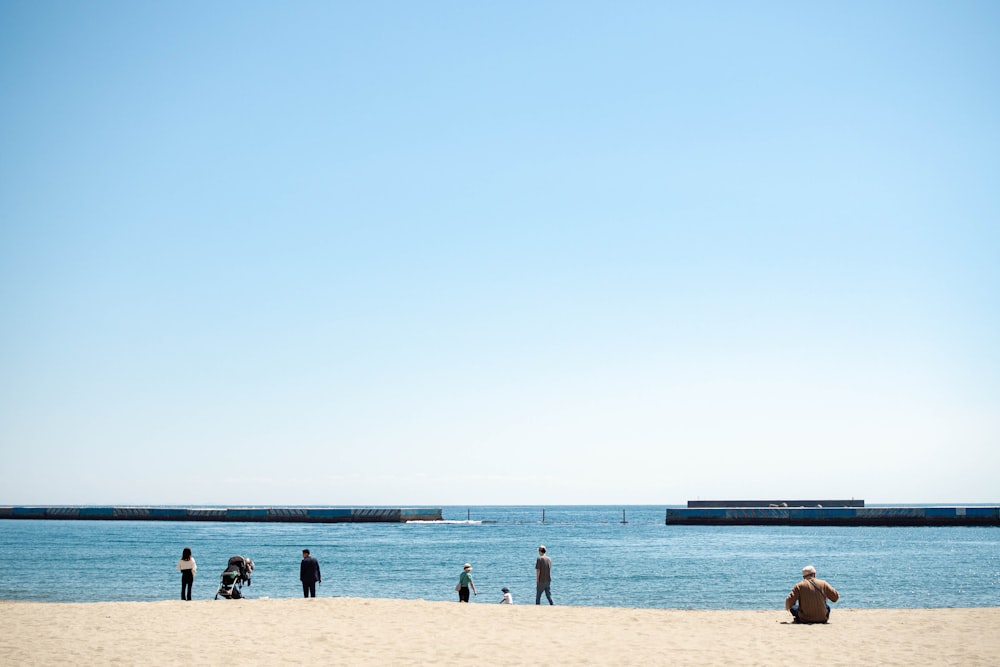 a group of people standing on top of a sandy beach