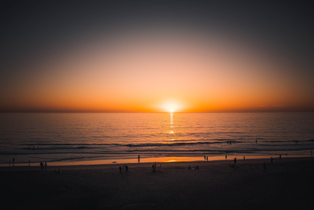 the sun is setting over the ocean on the beach