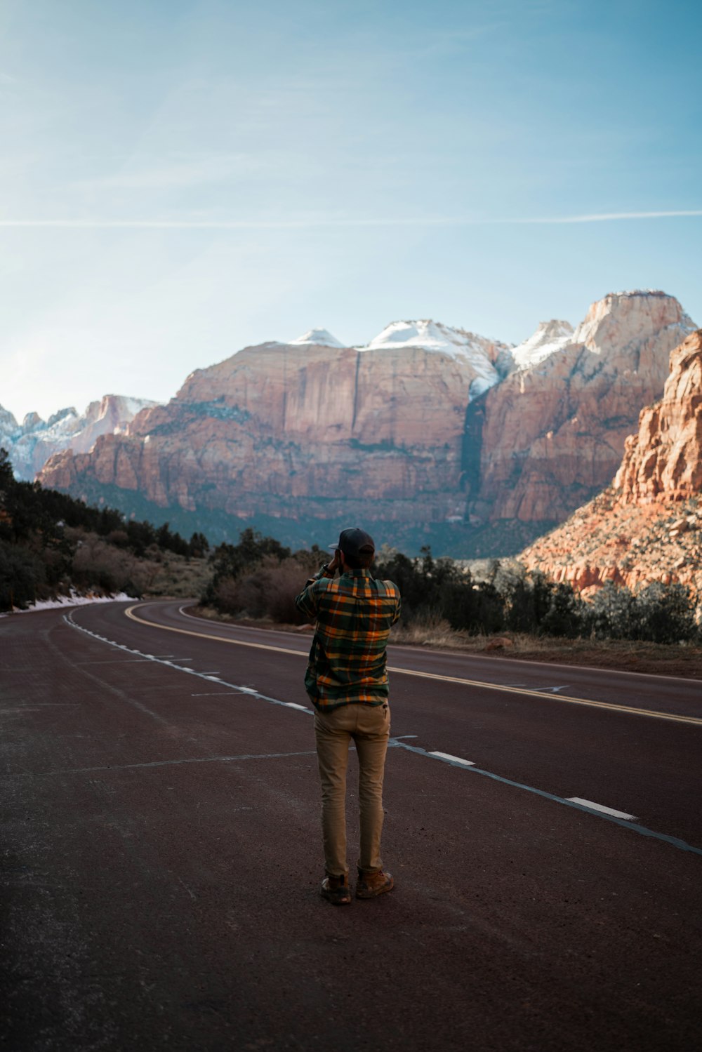 a man standing on the side of a road with mountains in the background