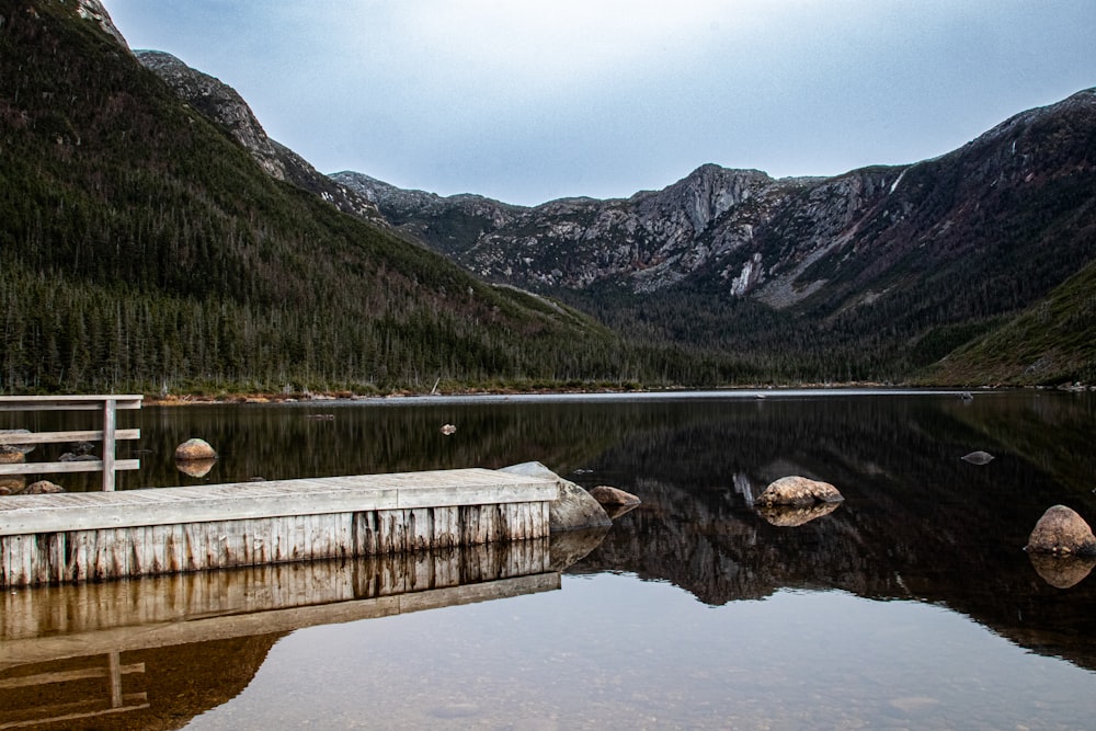 a wooden dock sitting on top of a lake surrounded by mountains