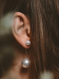 A model wearing pearl earrings in a natural setting.