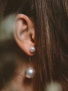 A model wearing pearl earrings in a natural setting.