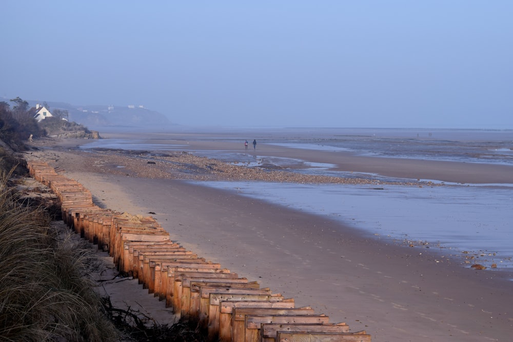 a person walking on a beach next to a fence