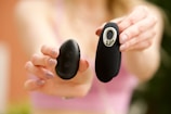 Close-up of hands comparing two electronic gadgets side by side.