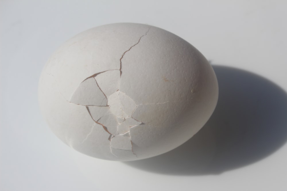 a cracked egg sitting on top of a white table