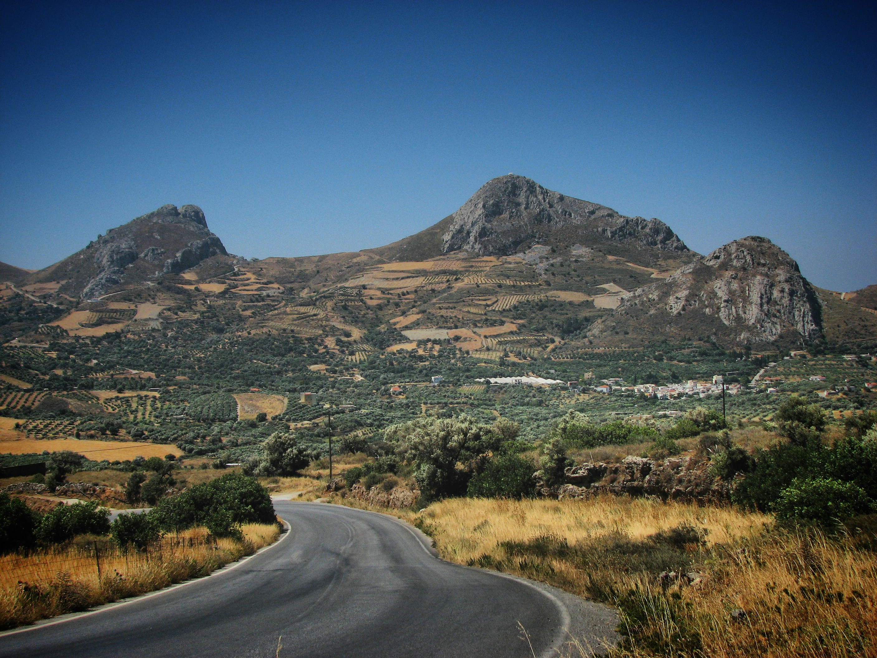 a road in the middle of a mountain range, Road in the mountains against clear blue sky in Crete, Greece, June 2008
