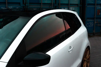a white car parked next to a blue container