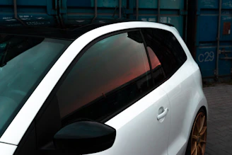 a white car parked next to a blue container