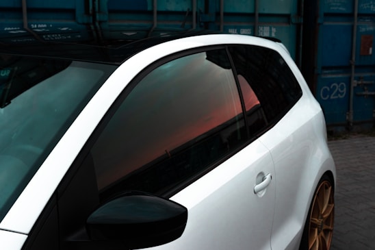 a white car parked next to a blue container