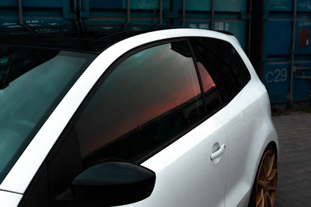 a white car parked next to a blue container