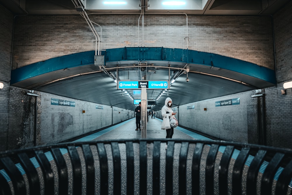 a woman in a white coat is standing in a subway