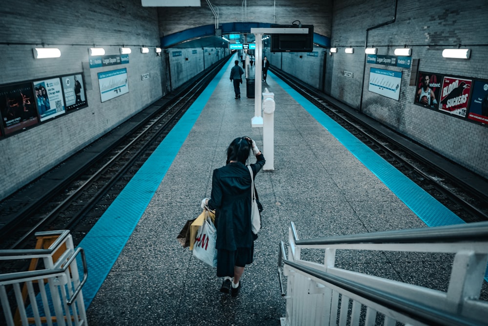 a woman walking down a subway platform carrying shopping bags