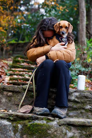 a woman sitting on a rock holding a dog