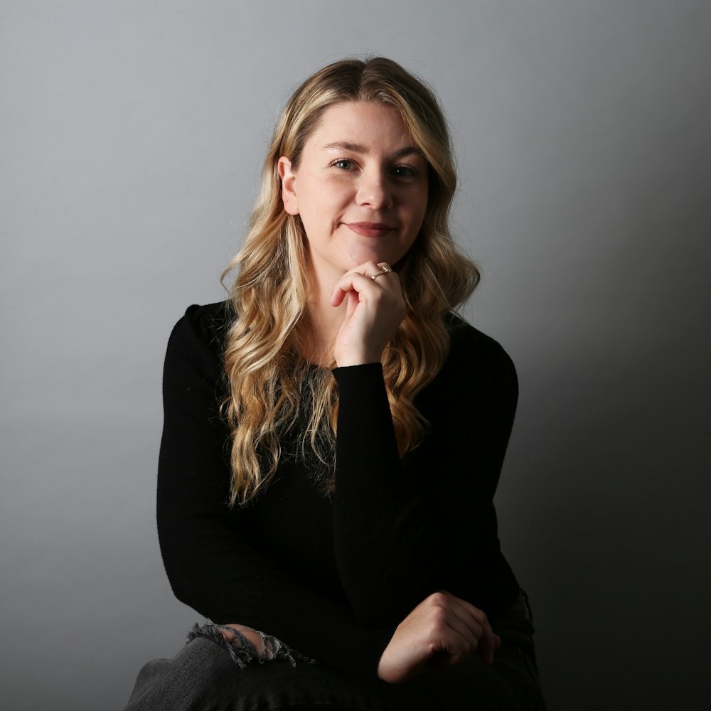 a woman sitting down with her hand on her chin