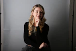 a woman sitting on a chair with her hand on her chin