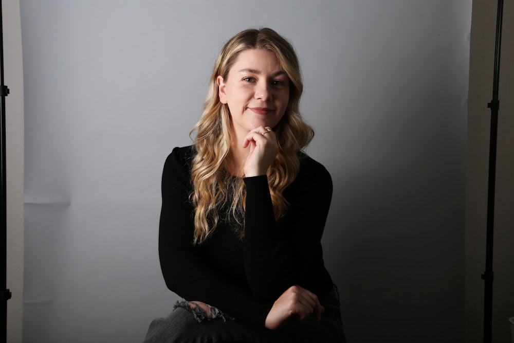 a woman sitting on a chair with her hand on her chin