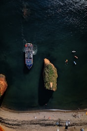 Drone filming a group of tourists enjoying a boat ride near the rocky coastline of Búzios.