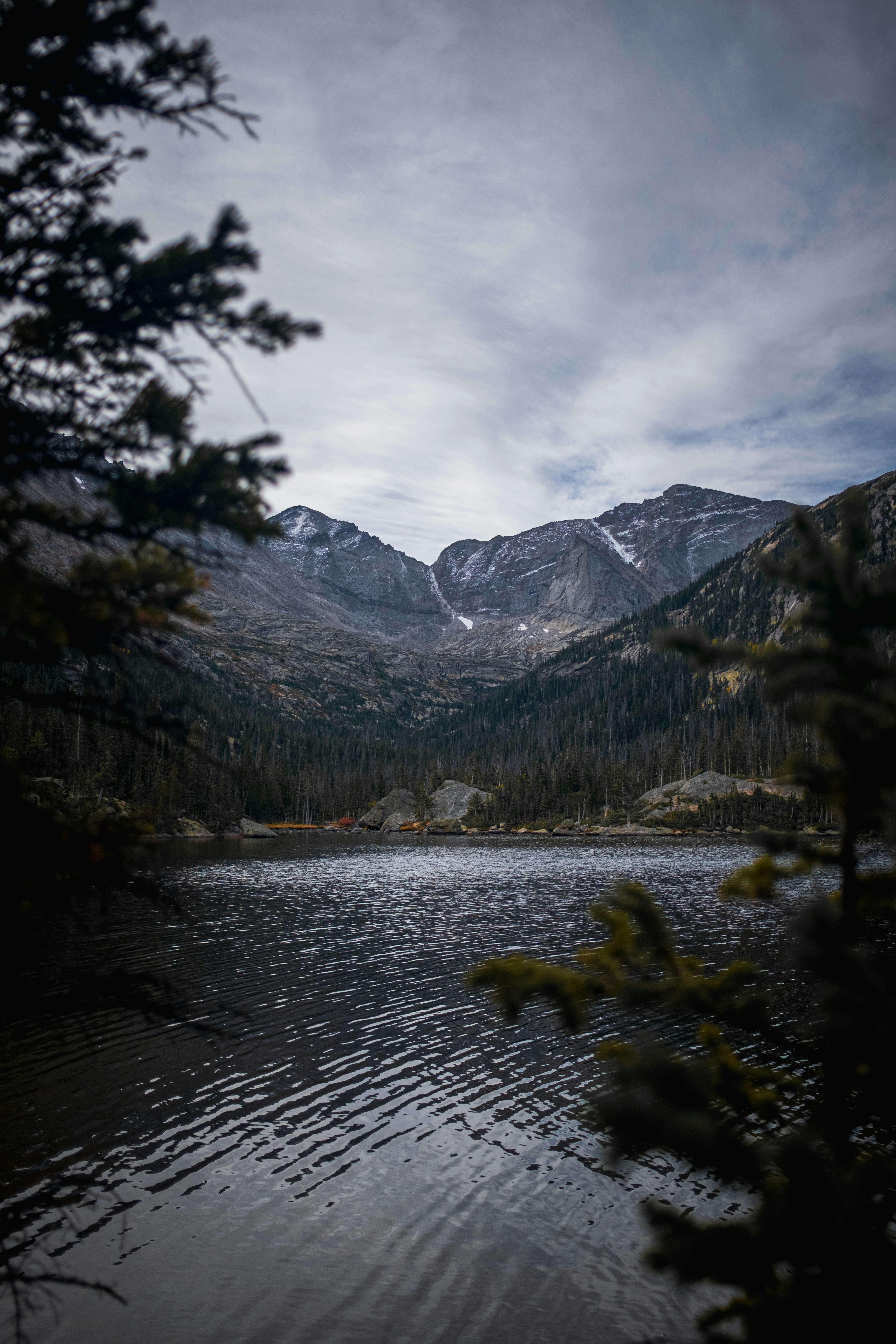 a body of water surrounded by mountains under a cloudy sky