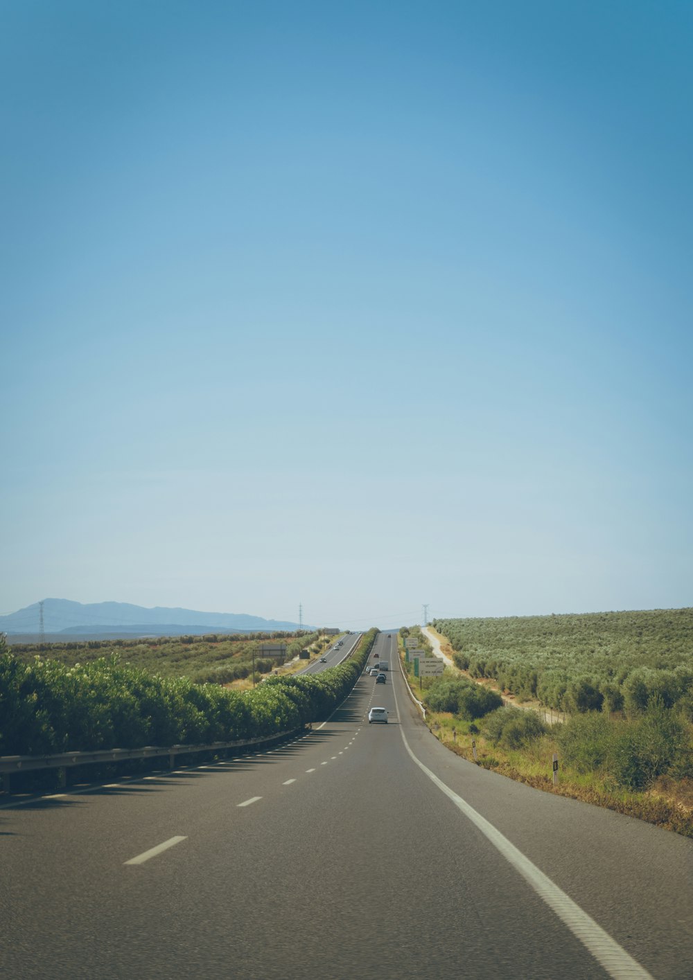 a long straight road with a blue sky in the background