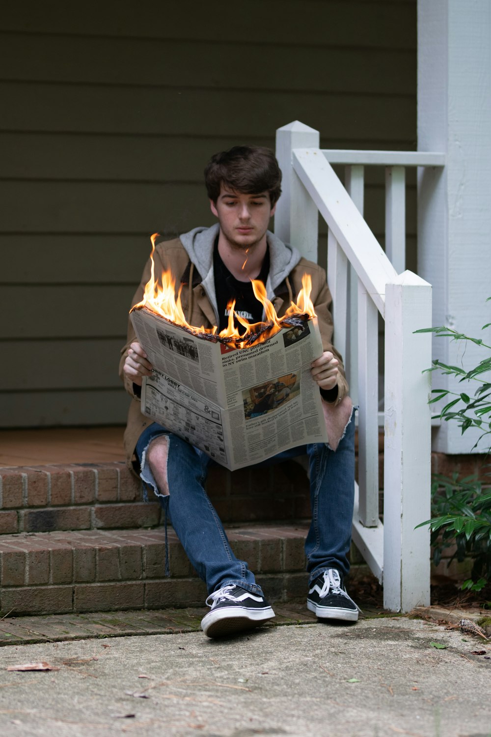 a young man sitting on the steps reading a newspaper