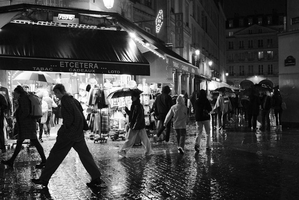 a black and white photo of people walking in the rain