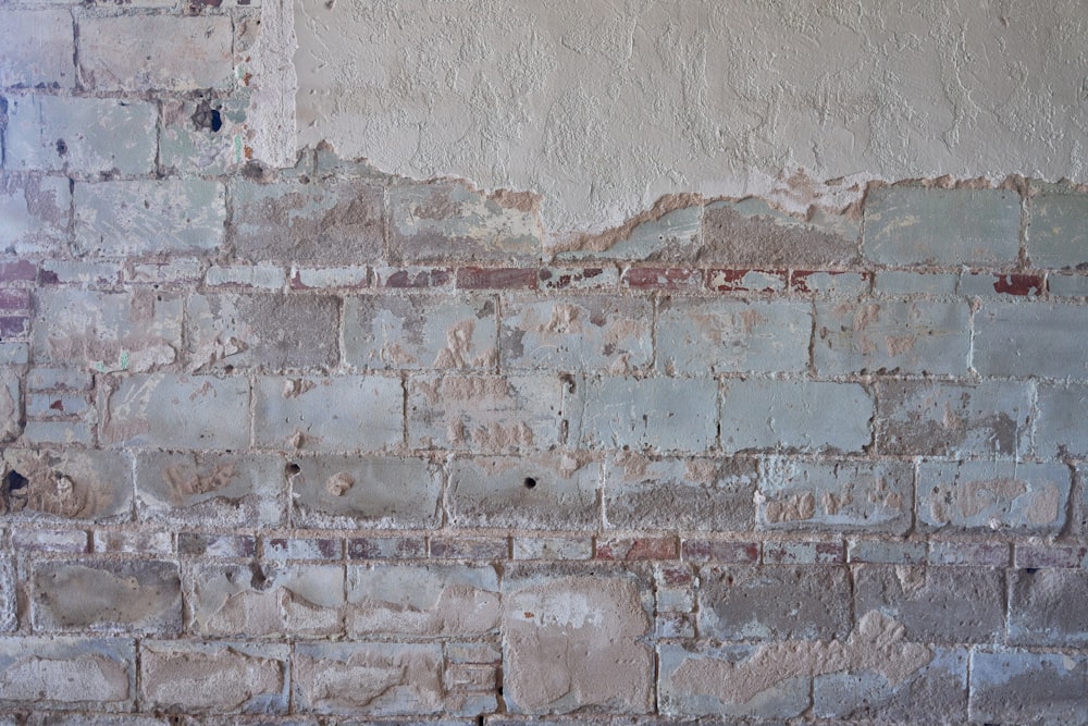 an old brick wall with peeling paint on it
