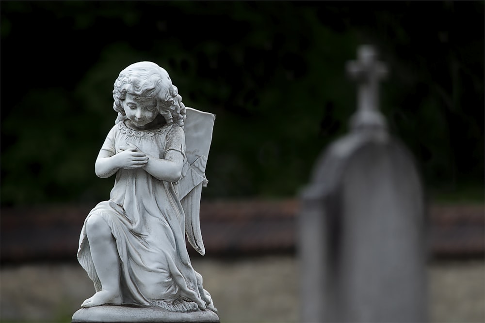 a statue of an angel sitting on top of a grave