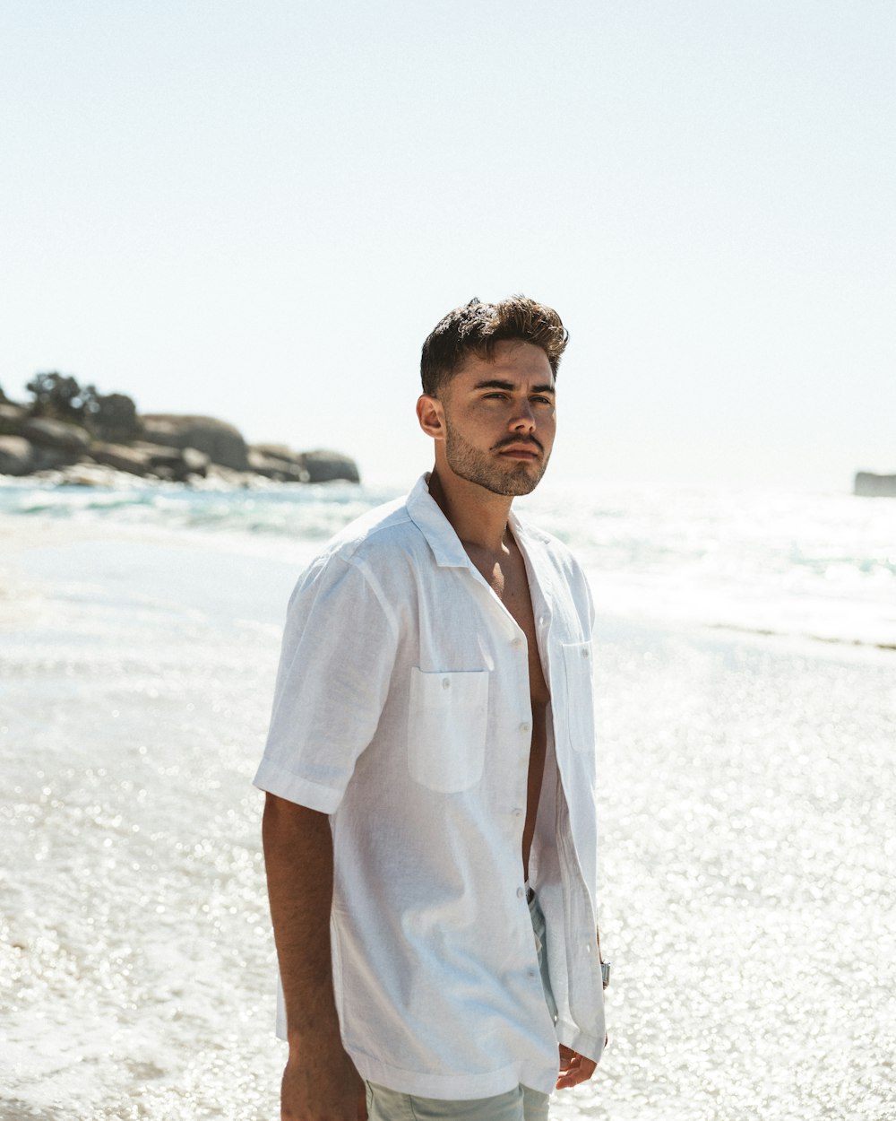 a man standing on a beach next to the ocean