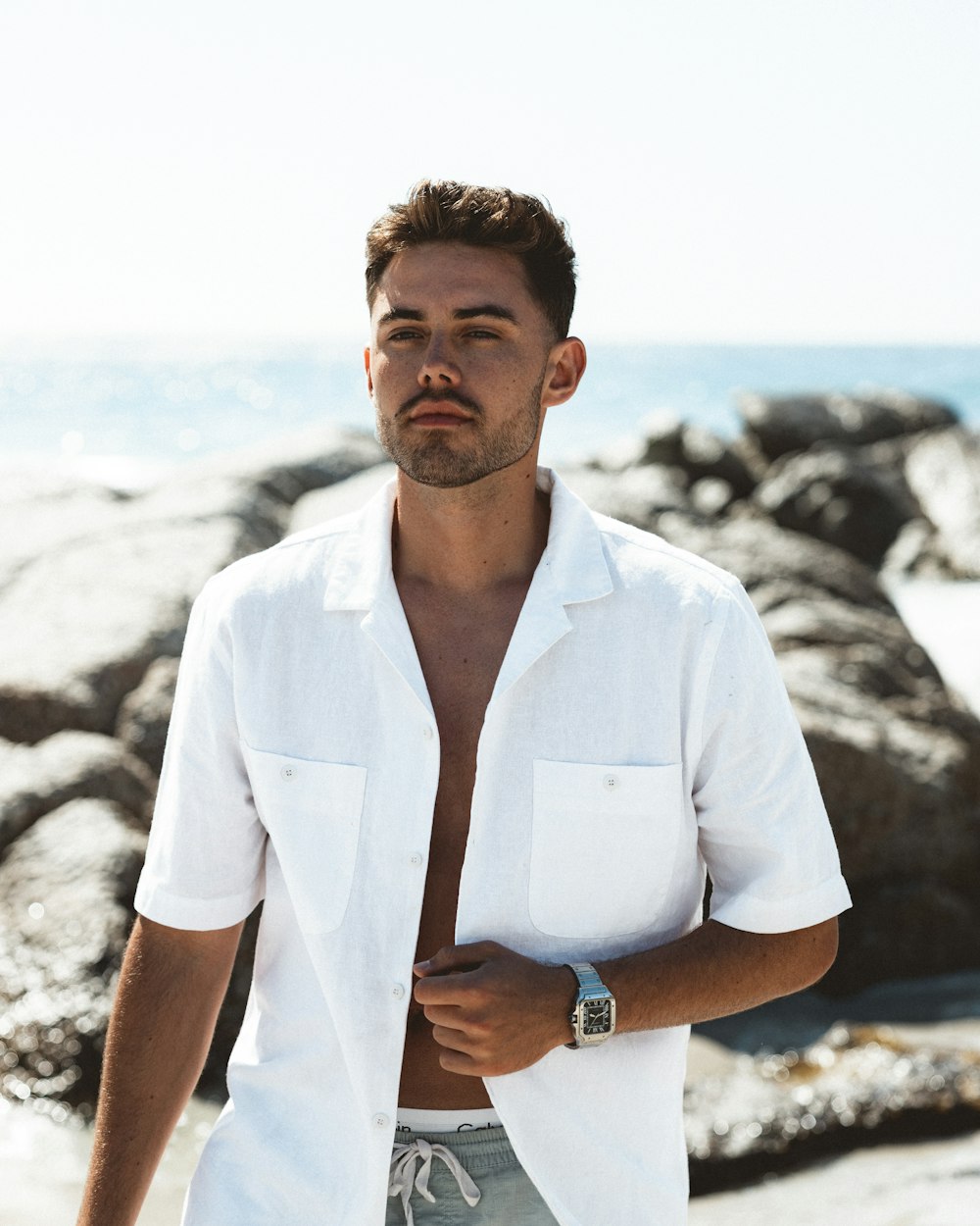 a man in a white shirt standing on a beach