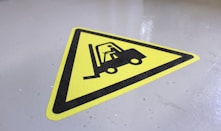 a yellow sign with a fork lift on it