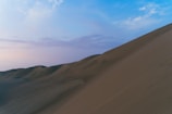 A peaceful desert scene with endless sand dunes under a vast, cloud-streaked sky.