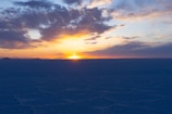 Sunset over the vast white salt flats with tourists exploring.