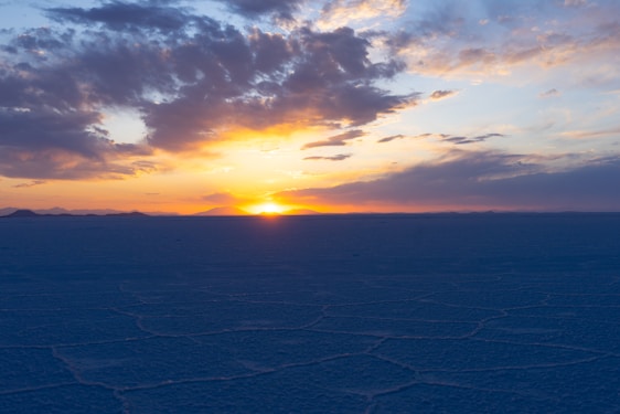 A vibrant photo of travelers enjoying the sunset over the Salar de Uyuni salt flats.