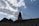 A silhouette of a church building with a cross on top is set against a blue sky with scattered clouds. Sunlight shines through the gaps in the clouds, creating a serene and calming atmosphere.